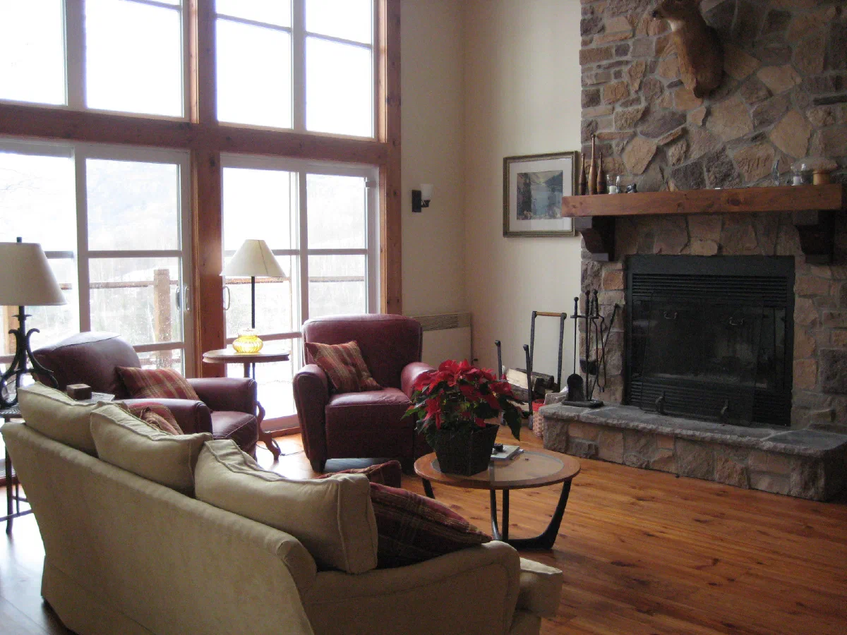 Chalet #05 — Living room with stone fireplace and tall windows