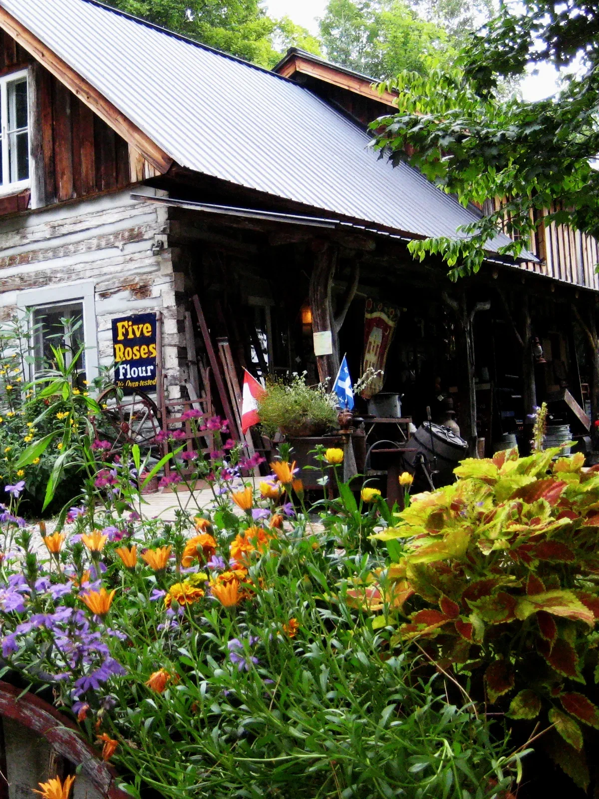 The Beggars Bench log shop and porch surrounded by flowers